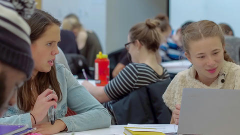 Close up of two students in discussion and working on computers