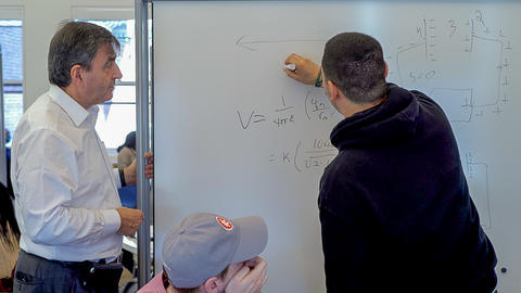 Faculty and student up at white board; student writing