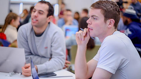 Close up of 2 students listening to other students in small group