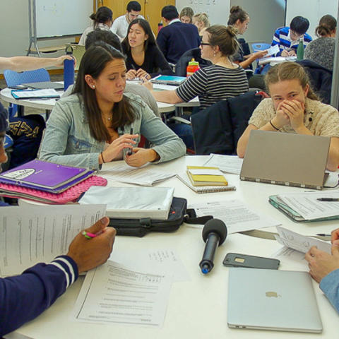 Small group of students working at a round table with computers